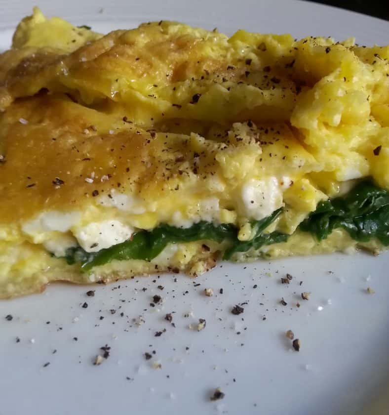 A close-up of a spinach and cheese omelette on a white plate, topped with cracked black pepper—perfect for a keto weight loss meal.
