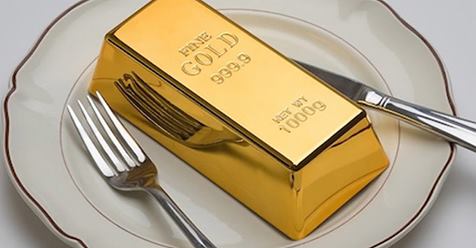 A large gold bar placed on a white plate with a fork and knife on either side, humorously symbolizing the rewards of keto weight loss—turning dietary dedication into pure gold.